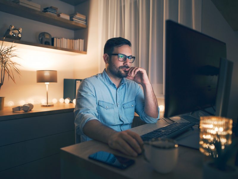 Young,Pensive,Man,Working,Remotely,From,Home,At,Night.